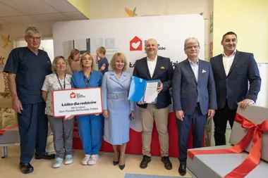Grupa osób, w tym personel medyczny i przedstawiciele fundacji, pozuje podczas uroczystego przekazania łóżek dla rodziców w placówce wspieranej przez Dom Ronald